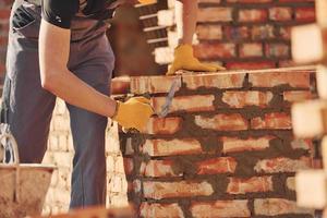 Busy with brick wall. Construction worker in uniform and safety equipment have job on building photo