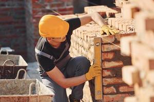 Measures of brick wall. Construction worker in uniform and safety equipment have job on building photo