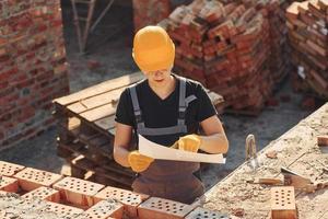 Holding plan in hands. Construction worker in uniform and safety equipment have job on building photo