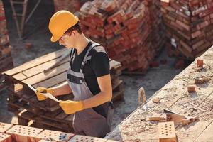 Holding plan in hands. Construction worker in uniform and safety equipment have job on building photo