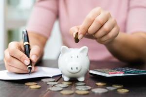 Closeup of woman hand putting money coin into piggy bank for saving money. saving money and financial concept photo