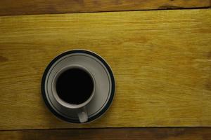 taza de café negro sobre un fondo de madera. área de espacio de copia foto