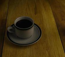 taza de café negro sobre un fondo de madera. área de espacio de copia foto