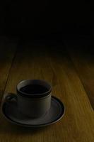 taza de café negro sobre un fondo de madera. área de espacio de copia foto