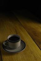 taza de café negro sobre un fondo de madera. área de espacio de copia foto