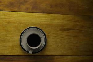 taza de café negro sobre un fondo de madera. área de espacio de copia foto