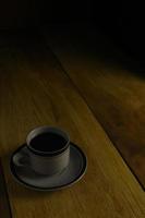 taza de café negro sobre un fondo de madera. área de espacio de copia foto