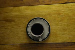 taza de café negro sobre un fondo de madera. área de espacio de copia foto