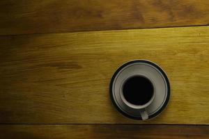 taza de café negro sobre un fondo de madera. área de espacio de copia foto