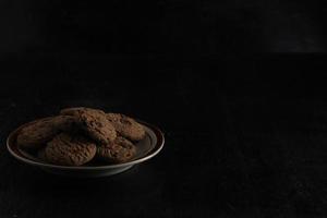 Chocolate chip cookies on plate on black background