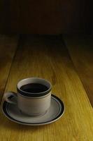 taza de café negro sobre un fondo de madera. área de espacio de copia foto