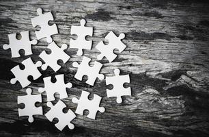 White details of jigsaw puzzle piece on wooden background. Concept of working together as a business team. The idea of getting involved, working for success. photo