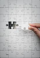 Pieces of jigsaw puzzle in woman's hands. White details of jigsaw puzzle piece on wooden background. Concept of working together as a business team. The idea of getting involved, working for success. photo