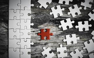 White details of jigsaw puzzle piece on wooden background. Concept of working together as a business team. The idea of getting involved, working for success. photo