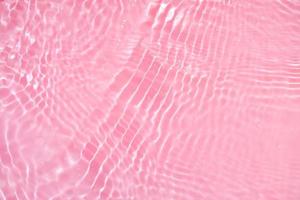 Defocus blurred transparent pink colored clear calm water surface texture with splashes and bubbles. Trendy abstract nature background. Water waves in sunlight with copy space. Pink watercolor shining photo