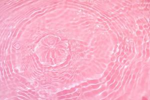 Defocus blurred transparent pink colored clear calm water surface texture with splashes and bubbles. Trendy abstract nature background. Water waves in sunlight with copy space. Pink watercolor shining photo