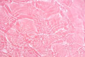 Defocus blurred transparent pink colored clear calm water surface texture with splashes and bubbles. Trendy abstract nature background. Water waves in sunlight with copy space. Pink watercolor shining photo