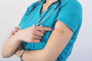 Young woman octor with adhesive bandage on her arm after Coronavirus vaccine. First aid. Medical, pharmacy and healthcare concept. photo