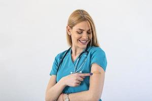 Young woman doctor with adhesive bandage on her arm after Coronavirus vaccine. First aid. Medical, pharmacy and healthcare concept. photo