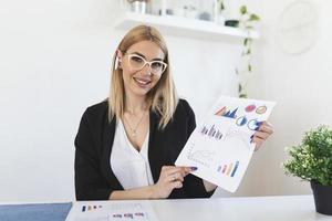 Focused business woman presenting charts and graphs on video call online. Young business woman having conference call with client on laptop. Young woman explaining how business work photo