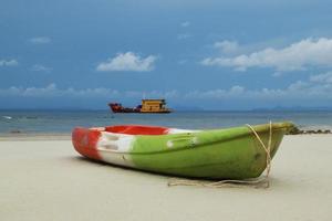 Travel to island Phi Phi, Thailand. The green-red-white boat on the sand beach with sea and blue sky on background. photo