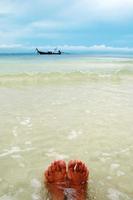 piernas de mujer a orillas del mar con agua clara y vistas al cielo azul. isla phi phi, tailandia. foto