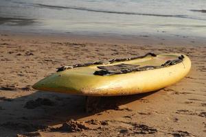 Travel to island Phuket, Thailand. Yellow surfboard closeup on the sand beach with sea on background. photo