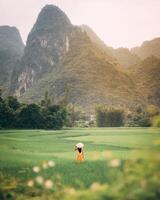 Photographer tourist traveler standing on green top on mountain holding in hands digital photo camera. Hiker taking photography, girl enjoy nature panoramic landscape in trip