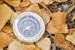 Compass lying in yellow autumn foliage.Concept recreation, travel, and tourism. photo