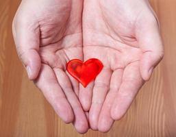 un corazón rojo en las palmas masculinas foto