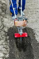 farmer prepares soil for seeding by tiller photo