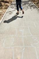 girl hops in hopscotch on urban alley photo