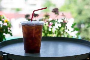 Ice black coffee or americano on dark table with green natural background. Energy drink in the morning concept. photo