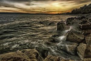 puesta de sol sobre el mar con olas salpicadas en las rocas foto