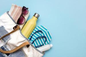 beach accessories in a beach bag on a blue background with copy space