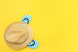 beach accessories - straw hat and flip flops on yellow background, summer background, copy space