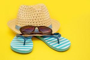 hat with sunglasses and striped flip flops on a yellow background photo