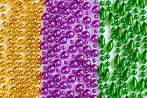 Mardi Gras background. Multi-colored beads close-up. Festive decorations in gold, green and purple colors. Fat Tuesday symbol. photo