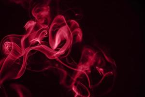 Red puffs of smoke on black background. Color of the year 2023 - Viva Magenta photo