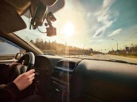 vista desde el coche hasta la carretera bajo el sol. el conductor conduce el vehículo. manos al volante. foto