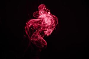 Unusual red smoke on black background. Color of the year 2023 - Viva Magenta photo