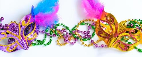 Two carnival masks with feathers and multi-colored beads on white background. Mardi Gras or Fat Tuesday symbol. photo