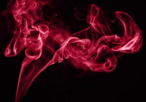 Beautiful red smoke on black background. Color of the year 2023 - Viva Magenta photo