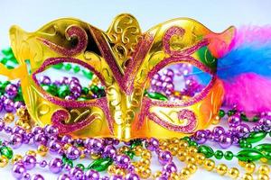 máscara de carnaval dorada y primer plano de cuentas de colores. mardi gras o símbolo del martes gordo. foto