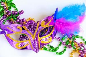 máscara de carnaval púrpura con plumas y primer plano de cuentas de colores. mardi gras o símbolo del martes gordo. foto