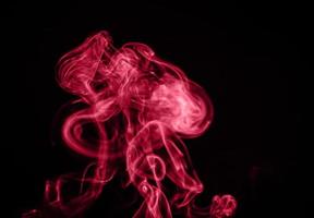 Unusual red smoke on black background. Color of the year 2023 - Viva Magenta photo