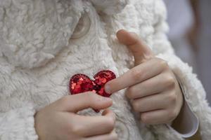 dedos apuntando a un corazón rojo en un abrigo de piel foto