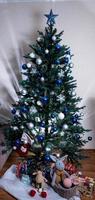 árbol de navidad con bolas de colores y cajas de regalo sobre una pared de ladrillo blanco con bolas azules y blancas foto