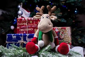 alce de punto. lindo alce juguete contra el fondo de una guirnalda de año nuevo, liebre tejida y alces en un árbol de navidad foto