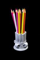 Color pencils for the drawing, located in a support as a vase, focus in front. multi-colored pencils and felt-tip pens in a plaster vase in the shape of a antique columnon a black background. photo